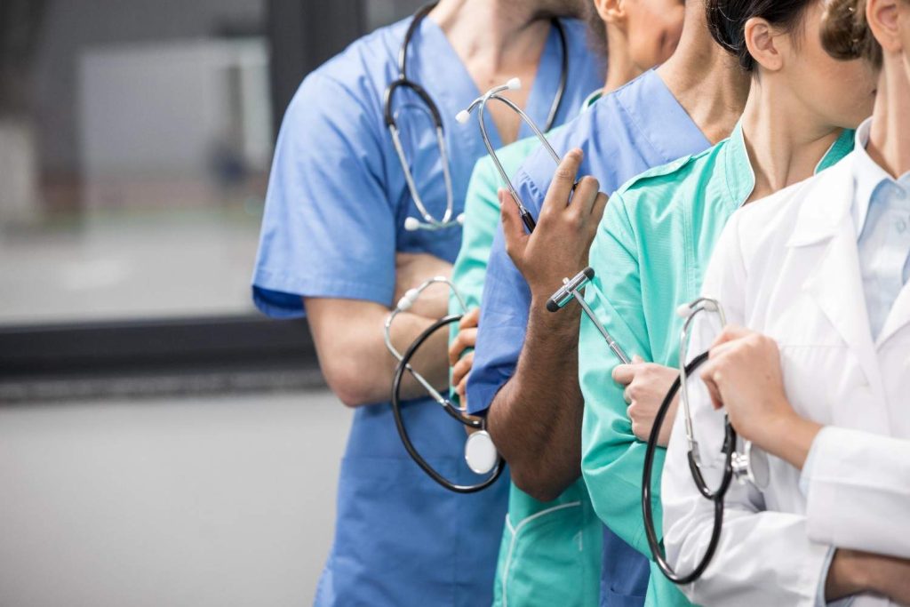 Diverse healthcare team in scrubs and lab coats, symbolizing comprehensive care at a walk-in clinic that accepts Ambetter insurance in Larchmont