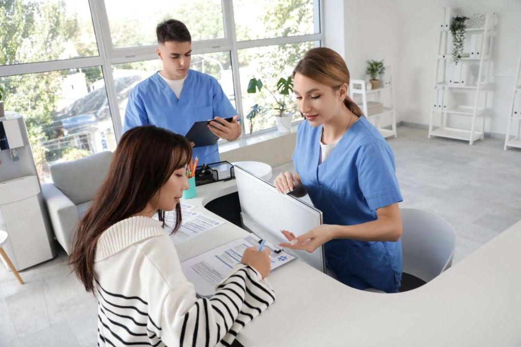 Medical receptionists assisting a patient at urgent care that accepts Ambetter insurance in Sharpstown.