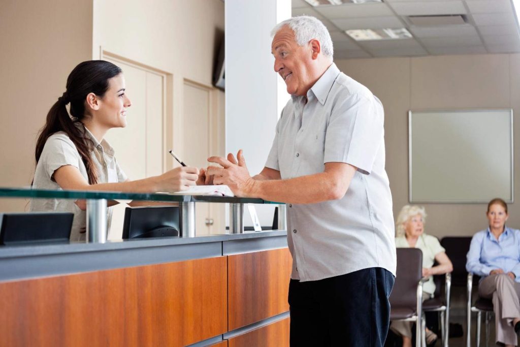 Senior man speaking with receptionist at an Ambetter approved urgent care Bellaire clinic