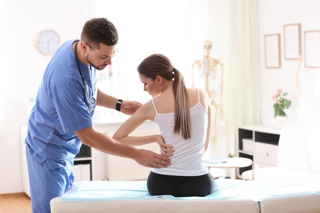 Doctor examining a patient's back pain at urgent care with Ambetter coverage in Sharpstown.