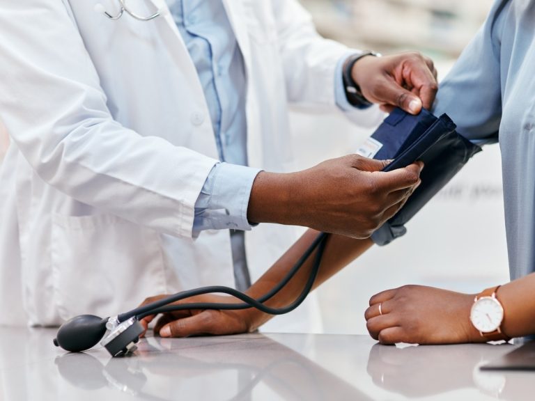 A healthcare professional using a blood pressure monitor on a patient at Urgent Care Services Houston.