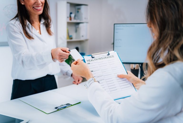 Ambetter accepted doctors Houston assist patient with insurance form and card during check-in at modern healthcare facility.