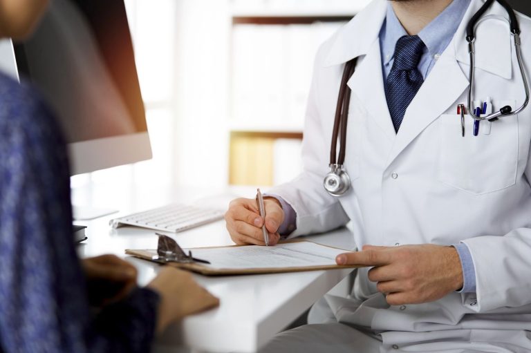 Patient consults with primary care doctor that takes Ambetter in professional office with stethoscope and medical notes.