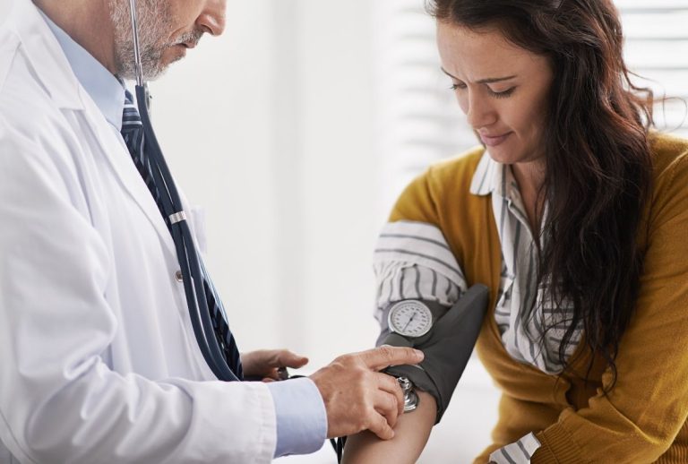 Nurse measuring blood pressure during an Annual Physical Exam, using a sphygmomanometer to monitor cardiovascular risk