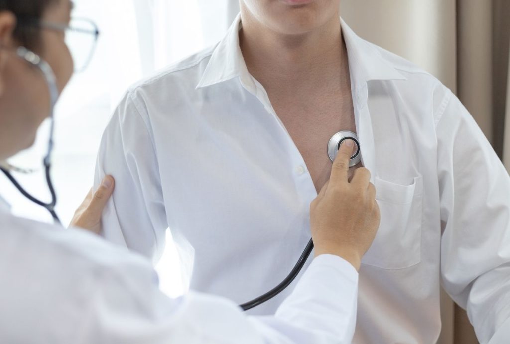 Physician listening to heart and lungs during an Annual Physical Exam, assessing cardiopulmonary health with a stethoscop