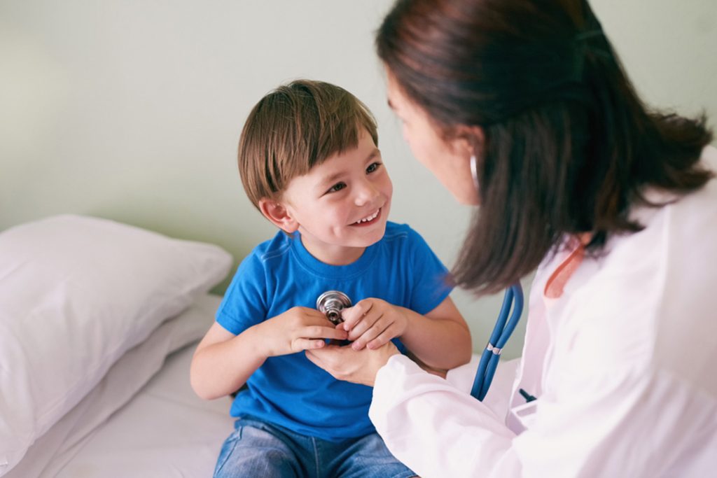 Urgent care services Houston doctor guiding child with stethoscope on bed, friendly pediatric visit in a calm medical setting