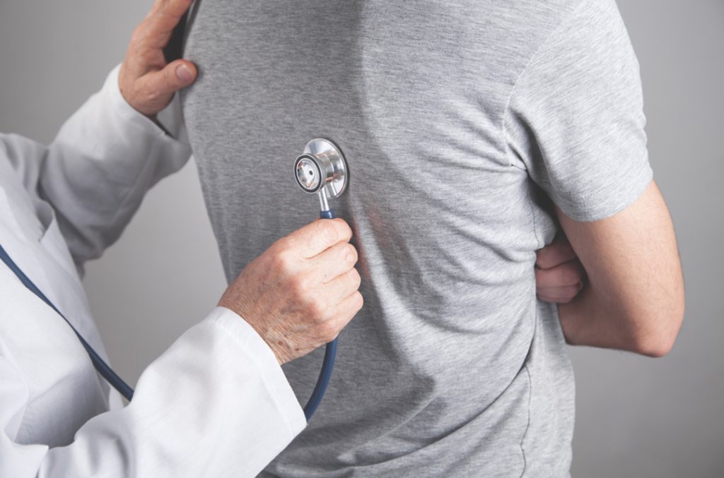 Urgent care open now Houston doctor using stethoscope on patient’s back, quick respiratory exam in convenient walk in clinic