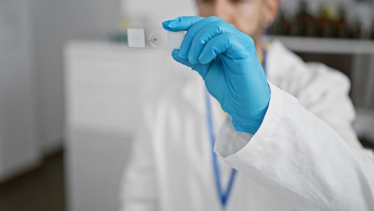 Lab technician examining a microscope slide for blood analysis at a walk-in clinic Ambetter insurance Houston.