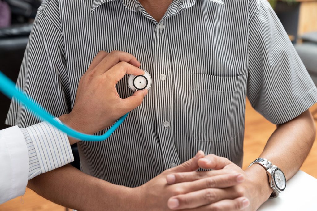 Urgent care open now Houston provider listening to patient heartbeat with stethoscope, same day cardiovascular check