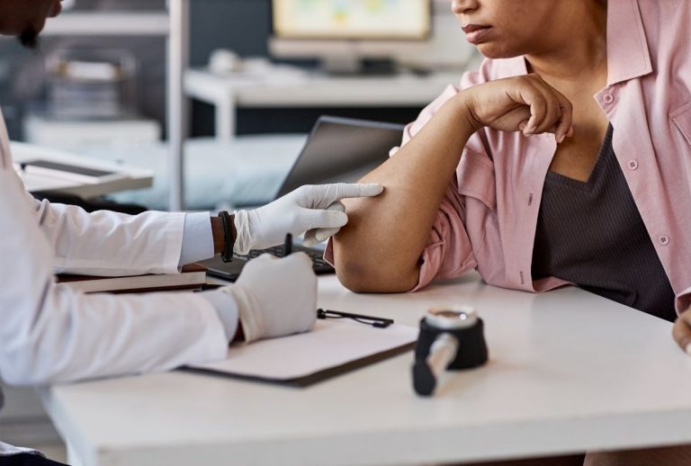 Healthcare provider in white coat examining a patient’s forearm during a Walk-In Clinic Houston consultation, highlighting personalized care and quick access to treatment.