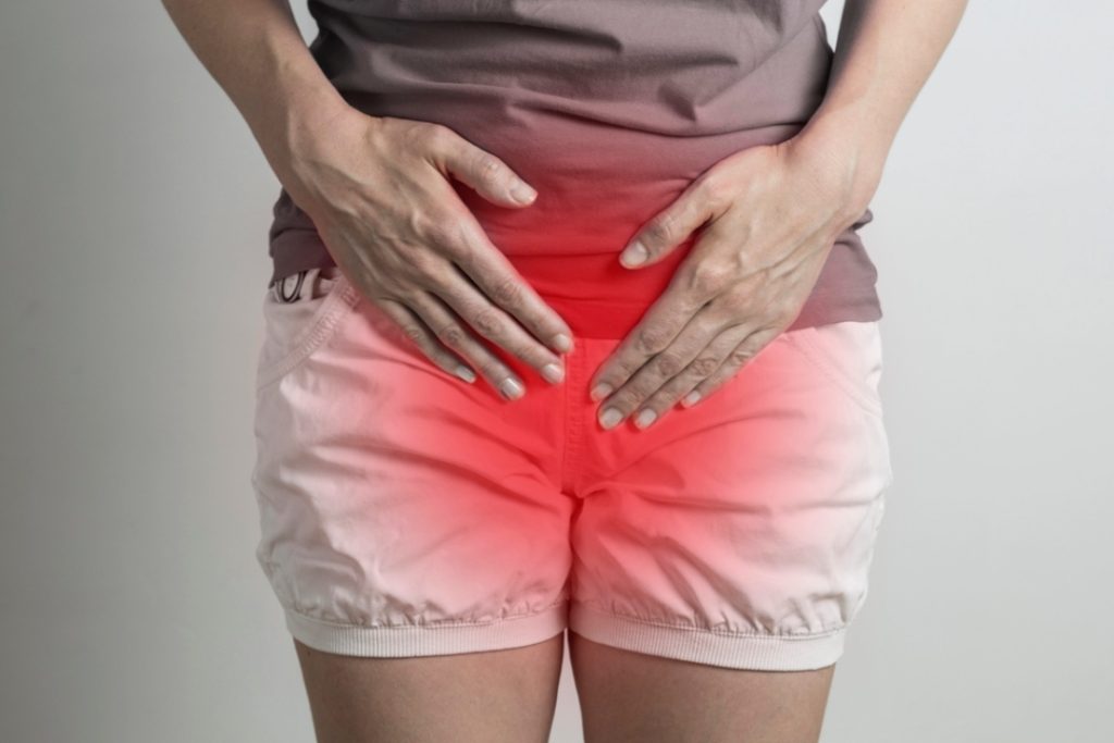 Woman holding lower abdomen with pain, illustrating common UTI symptoms and need for uti treatment houston care