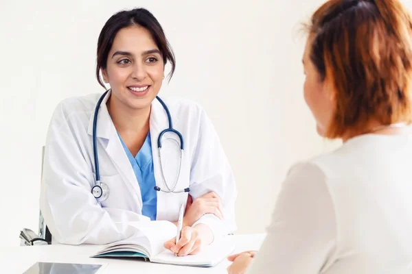 An experienced female doctor Houston smiles while discussing personalized medical treatment plans with her patient.