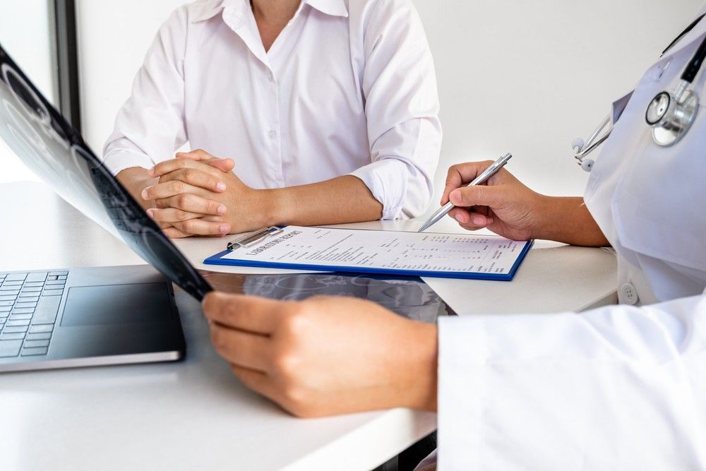 A doctor and patient consult at an Ambetter Health Urgent Care Clinic, reviewing an x-ray film and medical records.