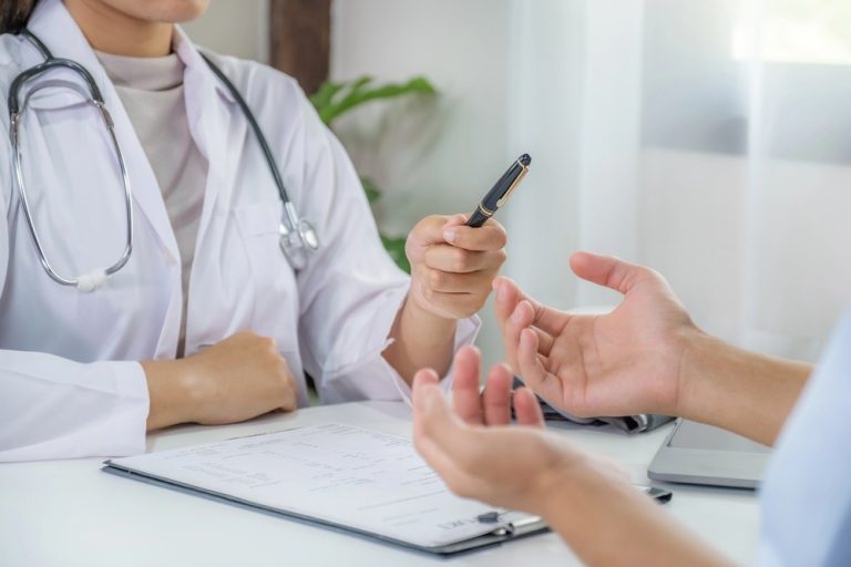 Doctor at clinics that accept Ambetter in Houston hands a pen to a patient filling out medical intake forms.