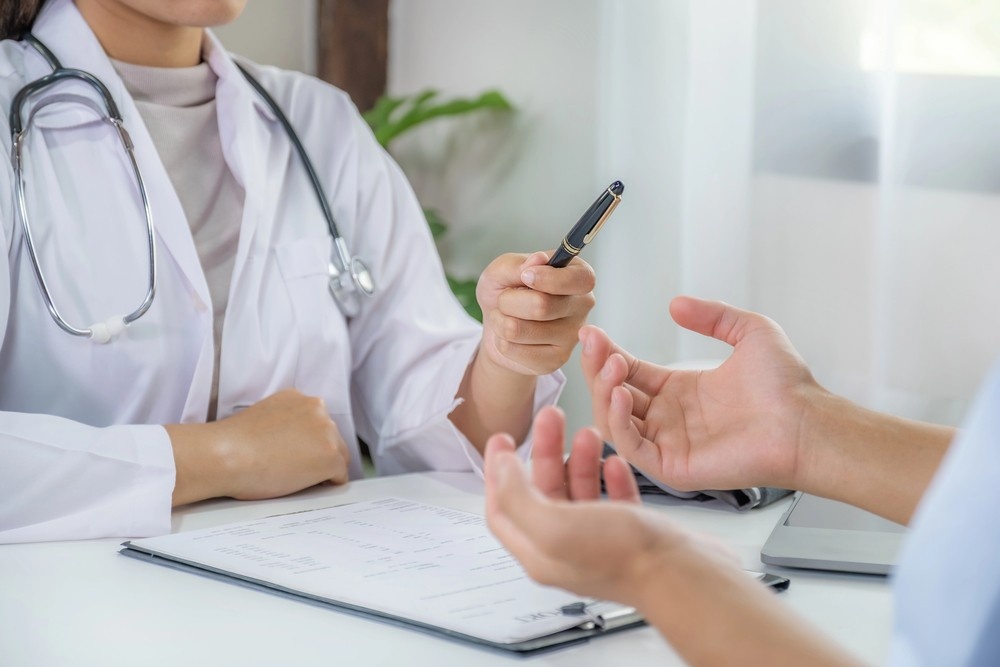Doctor at clinics that accept Ambetter in Houston hands a pen to a patient filling out medical intake forms.