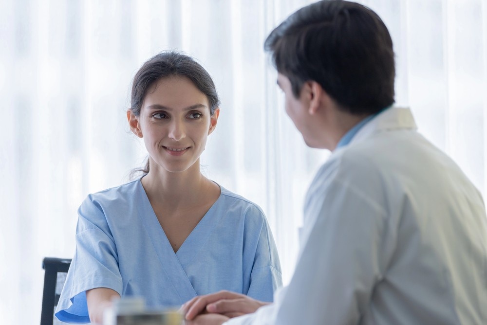 A doctor offers support to a smiling patient in a hospital gown. Find convenient care with a no appointment doctor Houston.