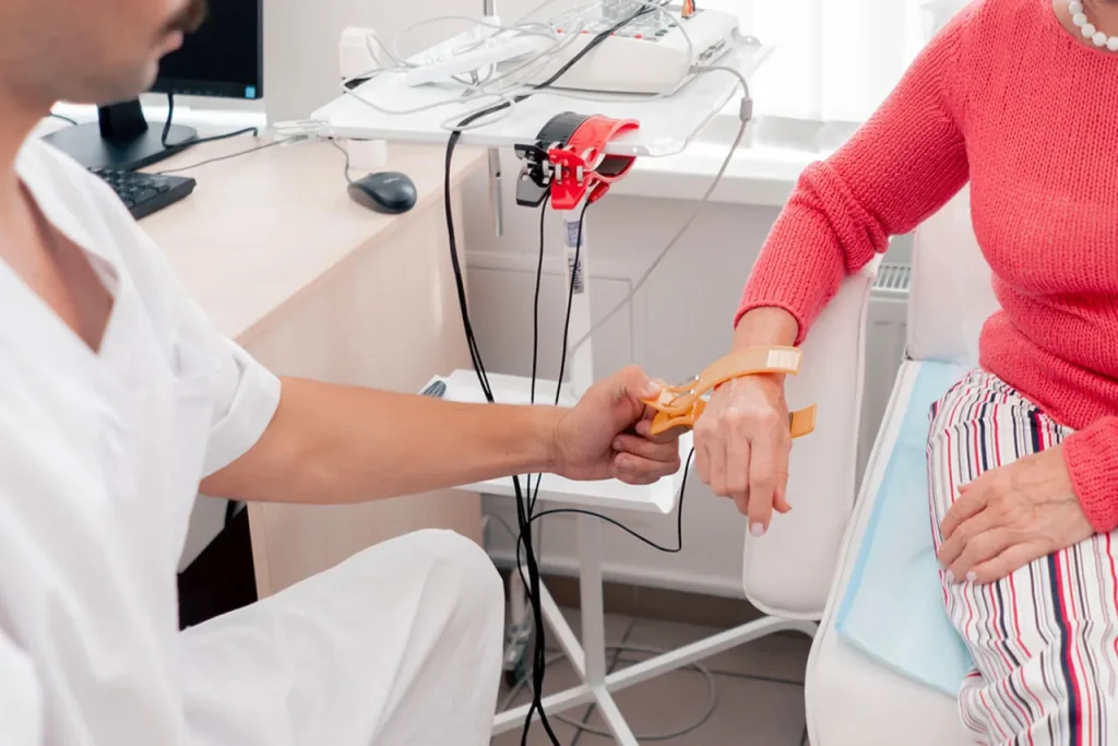 A doctor secures an EKG electrode clip onto a patient's wrist as part of comprehensive tests at an annual physical exam Houston clinic.
