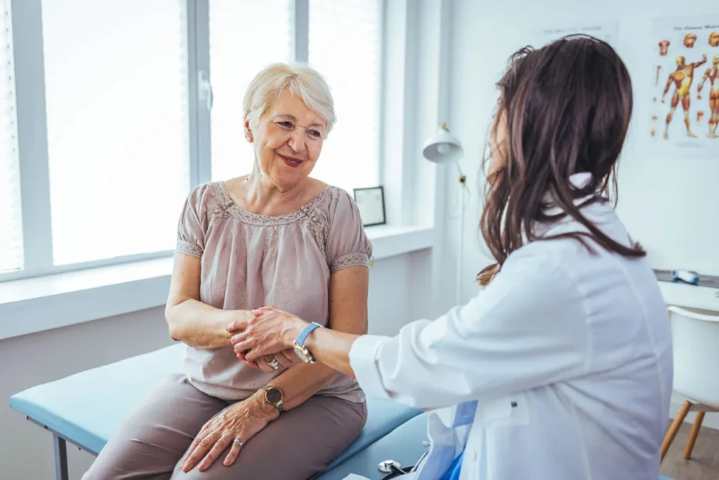 Elderly woman and a compassionate doctor hold hands and talk about health at a top-rated facility for an annual physical exam Houston.
