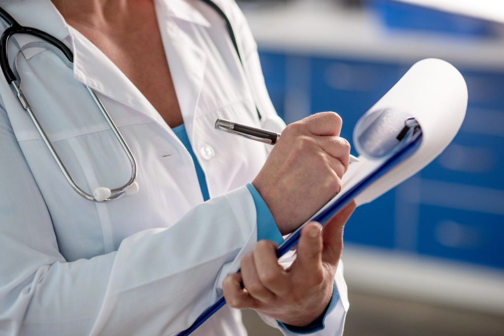 Close up of a dedicated female doctor Houston taking detailed notes on a medical clipboard for patient care records.