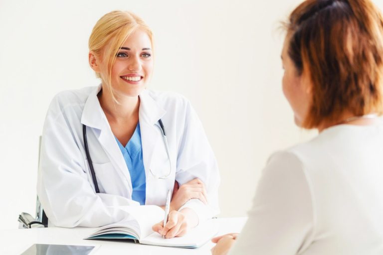 An experienced female doctor Houston smiles while discussing personalized medical treatment plans with her patient.