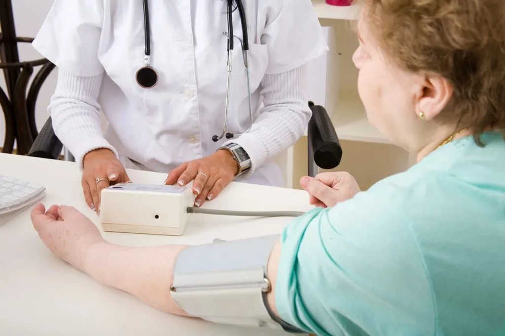 Medical professional monitors a patient's blood pressure and vital stats using a digital device at an annual physical exam Houston.