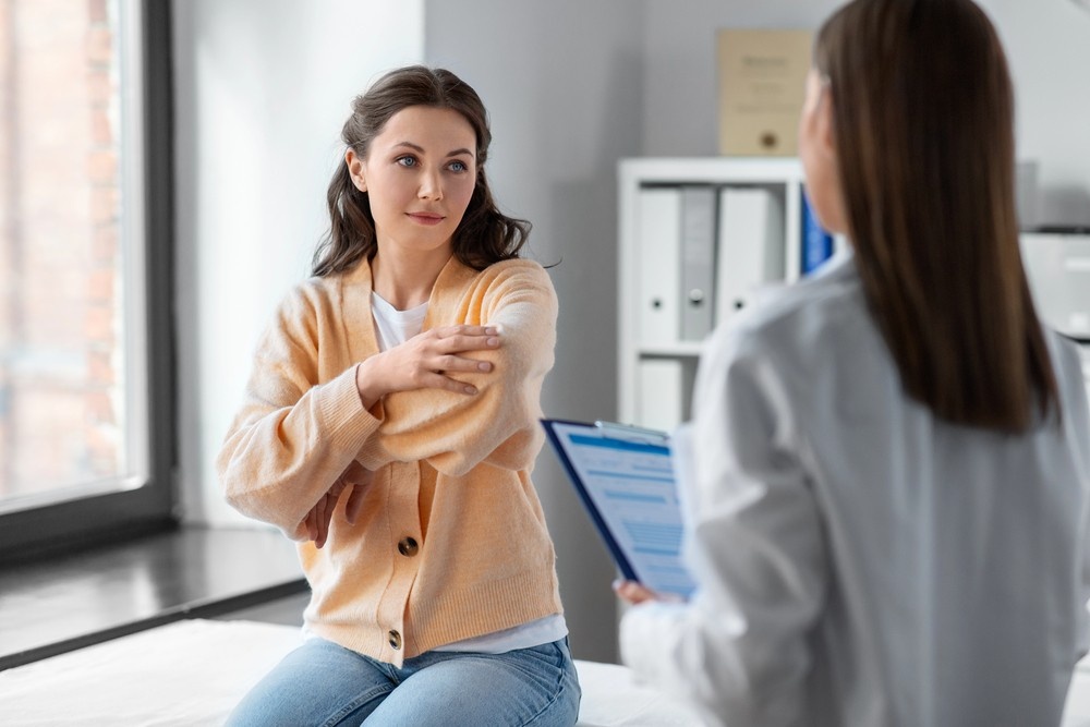 A patient on an exam table consults a doctor about an arm injury. Get walk-in medical care from a no appointment doctor Houston.
