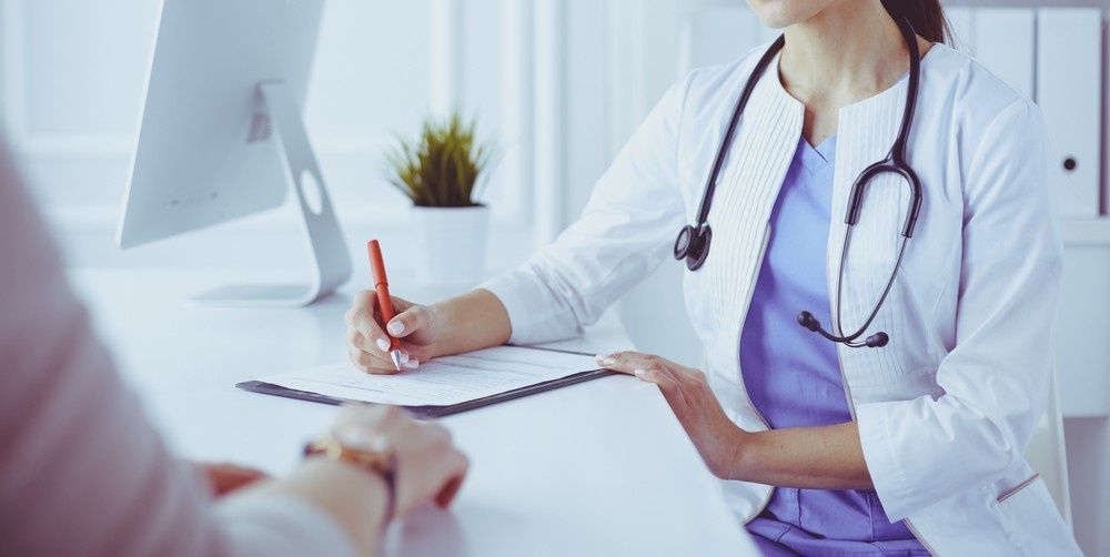 Physician at clinics that accept Ambetter in Houston updates a patient chart at her desk during a consultation.