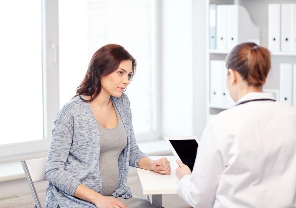 A pregnant patient speaks with a physician during a checkup. Access prenatal care easily at a no appointment doctor Houston clinic.