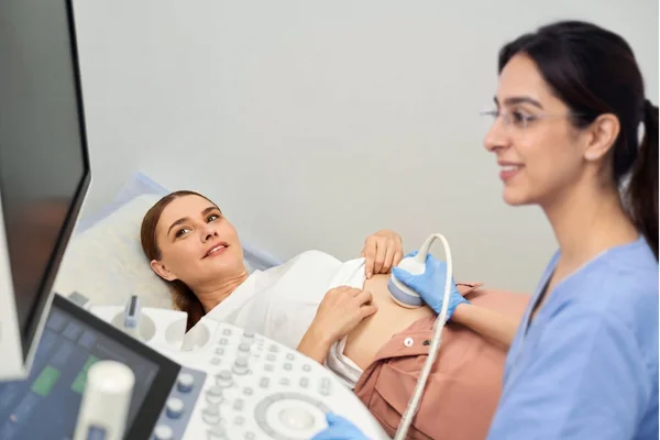 Female primary care doctor performing an abdominal ultrasound on a patient.